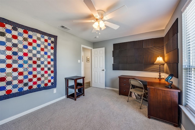 office space with ceiling fan, light colored carpet, visible vents, baseboards, and plenty of natural light