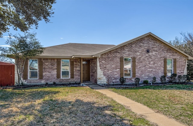 ranch-style home featuring brick siding, a front yard, and a shingled roof