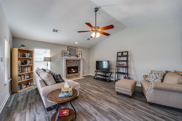 living area with dark wood-style floors, a fireplace, lofted ceiling, and visible vents