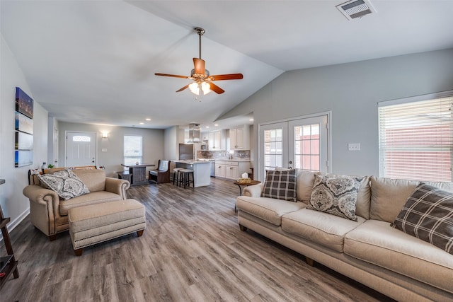 living room featuring french doors, lofted ceiling, visible vents, ceiling fan, and wood finished floors