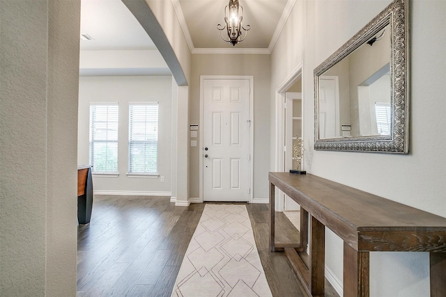 foyer with crown molding, wood-type flooring, and an inviting chandelier