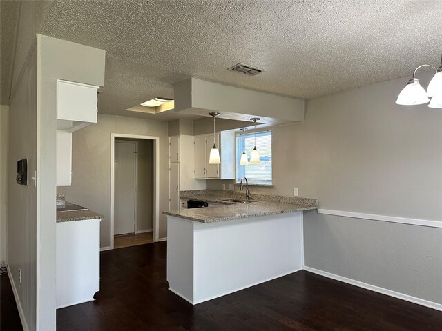 kitchen featuring appliances with stainless steel finishes, white cabinetry, a sink, and a peninsula