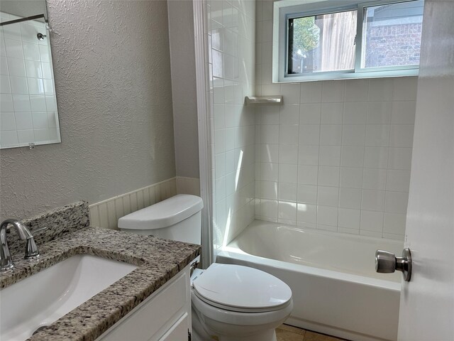 bathroom featuring a textured wall, bathing tub / shower combination, vanity, and toilet