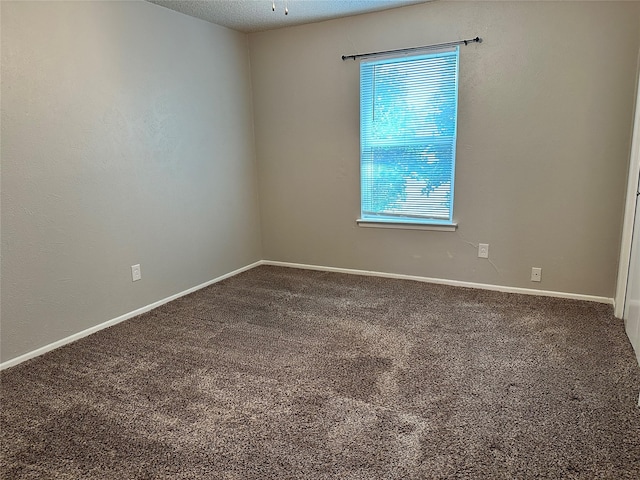 spare room with a textured ceiling, baseboards, and carpet flooring