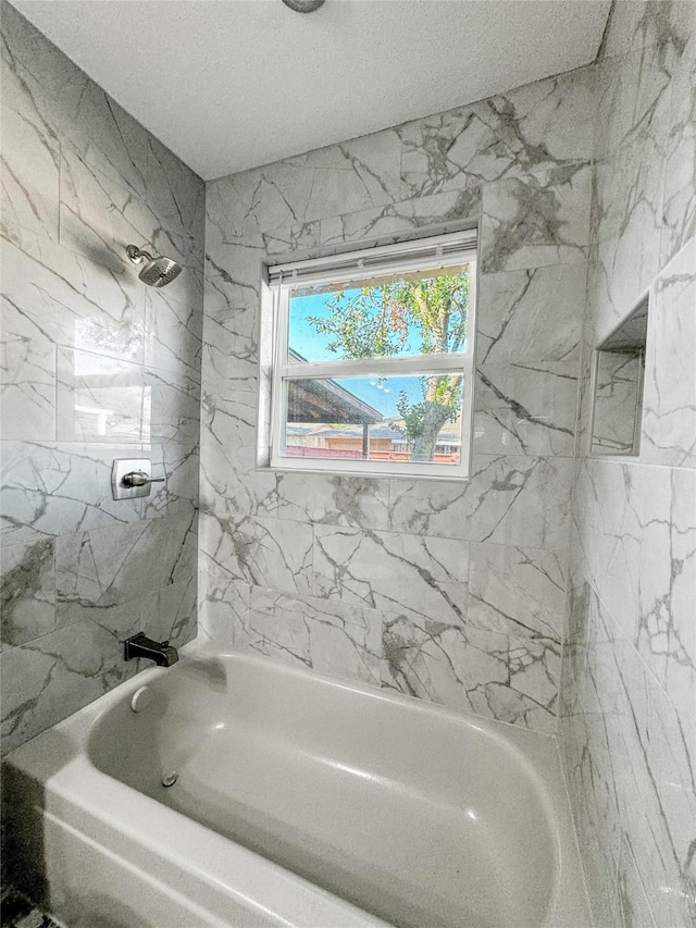 bathroom featuring tiled shower / bath combo and a textured ceiling