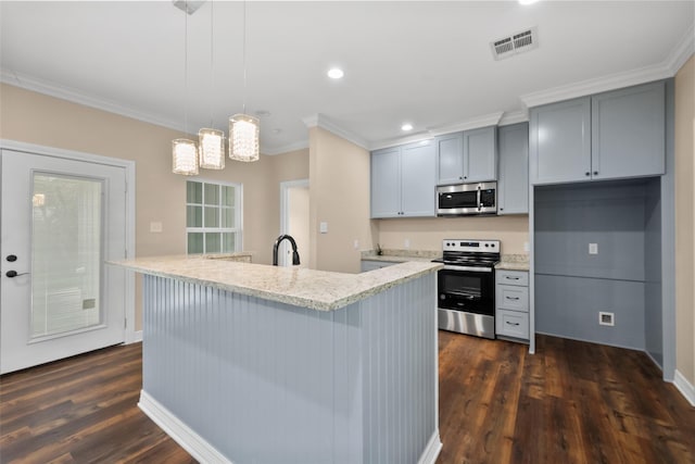 kitchen featuring crown molding, appliances with stainless steel finishes, a kitchen island with sink, light stone countertops, and decorative light fixtures