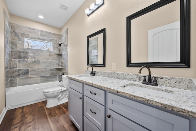 full bathroom featuring vanity, hardwood / wood-style floors, tiled shower / bath combo, and toilet