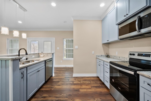 kitchen with pendant lighting, appliances with stainless steel finishes, sink, and light stone counters