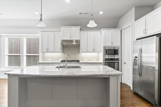 kitchen featuring white cabinetry, light stone counters, hanging light fixtures, an island with sink, and stainless steel appliances