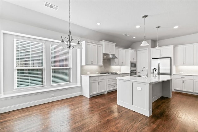 kitchen featuring hanging light fixtures, white cabinetry, a kitchen island with sink, and built in appliances