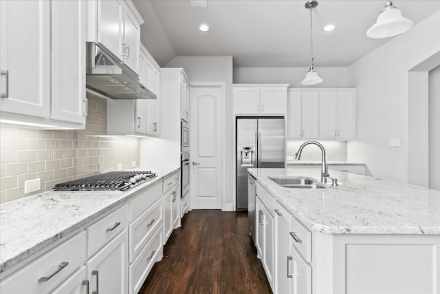 kitchen featuring decorative light fixtures, stainless steel appliances, an island with sink, and white cabinets