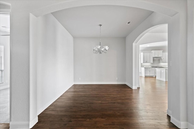 unfurnished dining area featuring an inviting chandelier and dark wood-type flooring