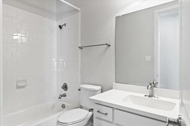 full bathroom featuring tiled shower / bath, vanity, and toilet