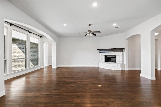 unfurnished living room featuring a fireplace, dark hardwood / wood-style floors, and ceiling fan