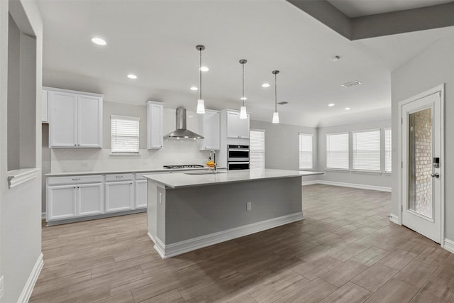 2700 Wallingford Dr, Mansfield, TX 76084 - kitchen featuring wall chimney range hood, white cabinets, double oven, light wood finished floors, and recessed lighting