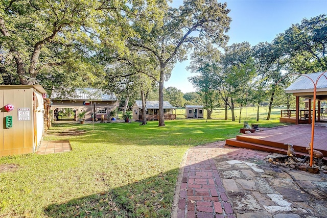 view of yard with a wooden deck, an outbuilding, and a patio