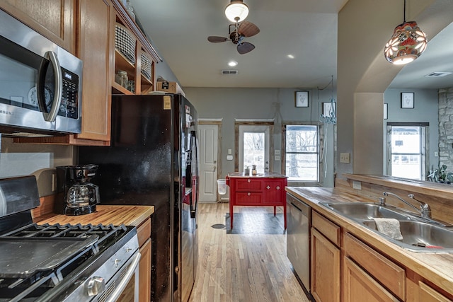 kitchen featuring sink, butcher block countertops, light wood-type flooring, ceiling fan, and stainless steel appliances