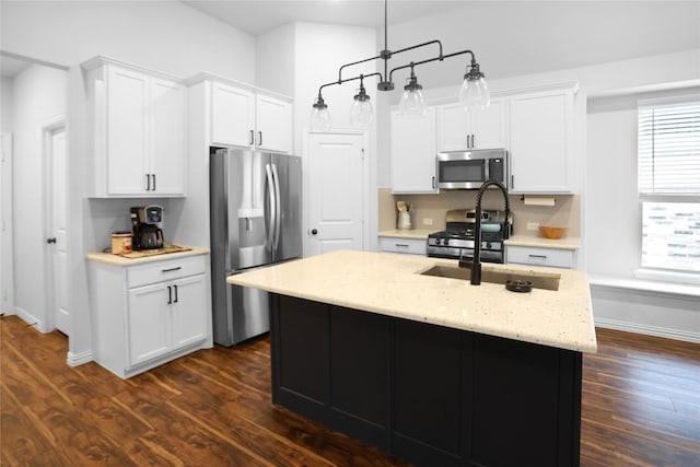 kitchen featuring white cabinetry, appliances with stainless steel finishes, an island with sink, and decorative light fixtures