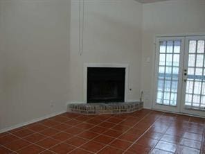 unfurnished living room with a brick fireplace, a healthy amount of sunlight, and tile patterned floors