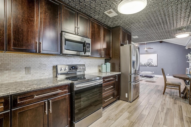 kitchen featuring tasteful backsplash, dark brown cabinets, light hardwood / wood-style flooring, stainless steel appliances, and light stone countertops