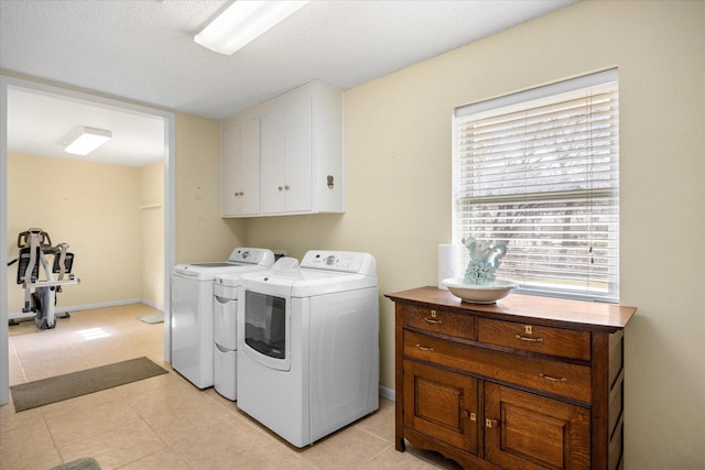 laundry area with cabinets, separate washer and dryer, and light tile patterned floors