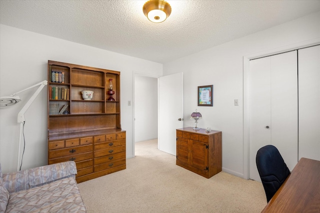 carpeted home office featuring a textured ceiling