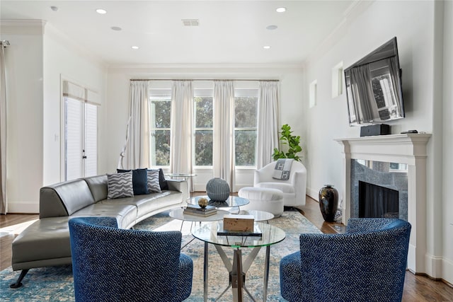 living room featuring hardwood / wood-style flooring, ornamental molding, and a fireplace