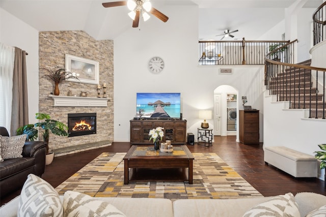 living room with washer / dryer, wood-type flooring, high vaulted ceiling, ceiling fan, and a fireplace