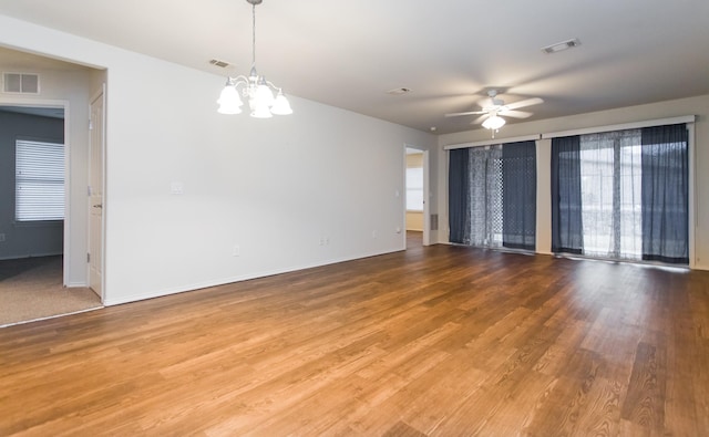 empty room featuring ceiling fan with notable chandelier and hardwood / wood-style floors