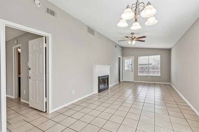 unfurnished living room with lofted ceiling, light tile patterned floors, a fireplace, a textured ceiling, and ceiling fan with notable chandelier