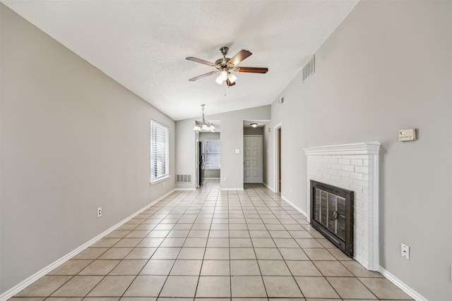 unfurnished living room with ceiling fan with notable chandelier, a fireplace, lofted ceiling, light tile patterned floors, and a textured ceiling