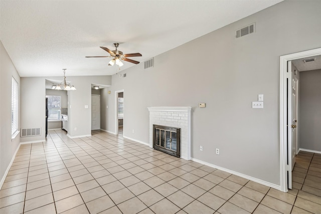 unfurnished living room featuring vaulted ceiling, ceiling fan with notable chandelier, light tile patterned floors, a brick fireplace, and a textured ceiling