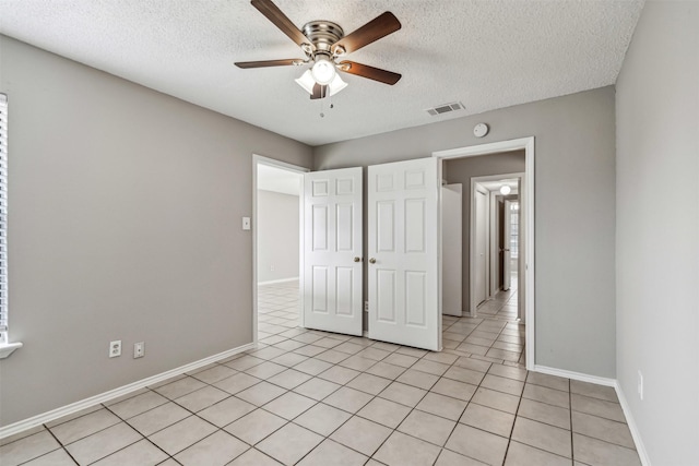 unfurnished bedroom with ceiling fan, light tile patterned floors, and a textured ceiling