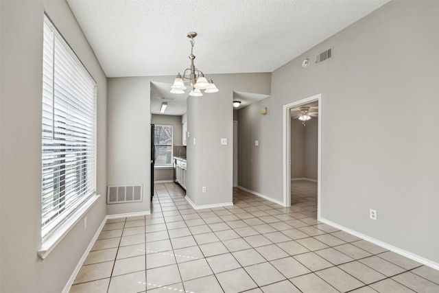 unfurnished dining area featuring a wealth of natural light, a textured ceiling, and light tile patterned flooring