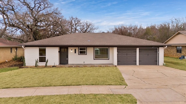 ranch-style house with a garage, brick siding, driveway, roof with shingles, and a front yard