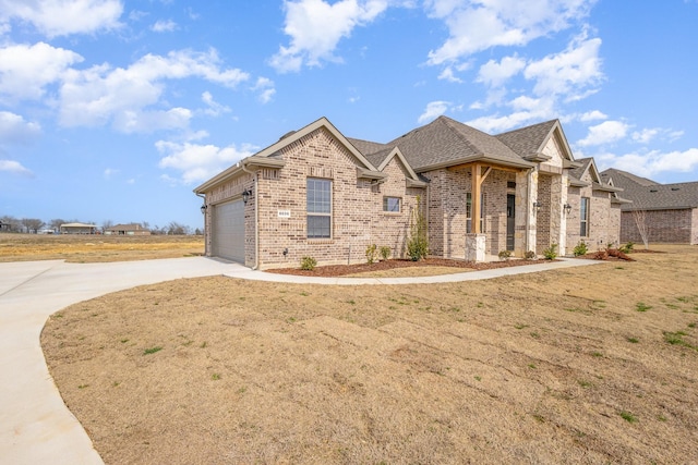 view of front of home with a shingled roof, brick siding, driveway, and an attached garage