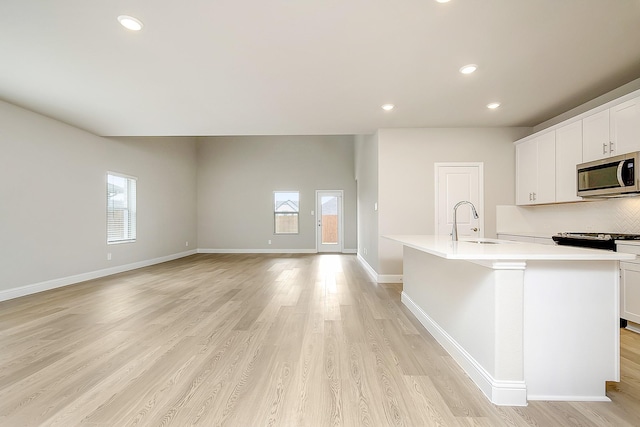 kitchen with a wealth of natural light, an island with sink, and white cabinets