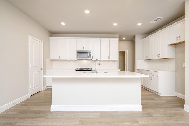 kitchen featuring white cabinetry, sink, a center island with sink, and light hardwood / wood-style flooring