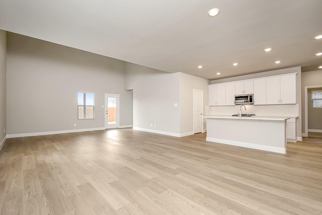 unfurnished living room featuring sink and light hardwood / wood-style flooring