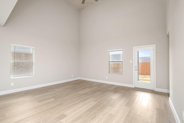 empty room featuring light hardwood / wood-style flooring, ceiling fan, and a high ceiling