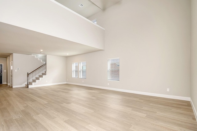 spare room with a towering ceiling and light hardwood / wood-style floors