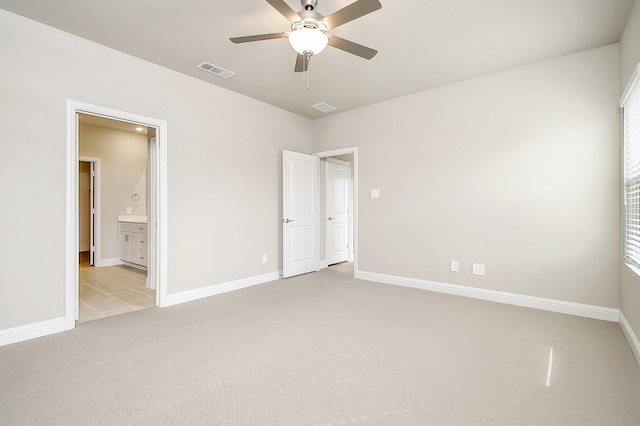 unfurnished bedroom featuring connected bathroom, light colored carpet, and ceiling fan