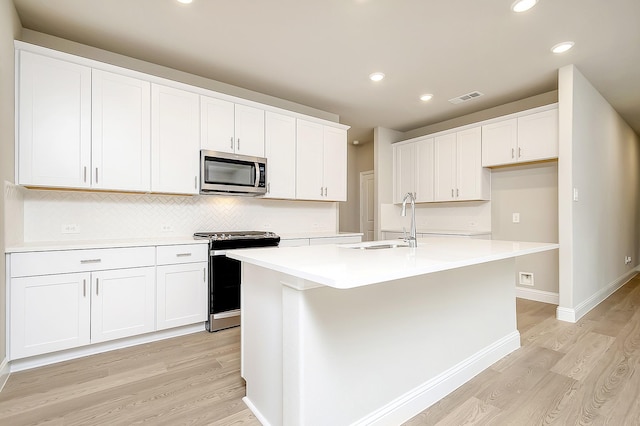 kitchen featuring white cabinetry, appliances with stainless steel finishes, sink, and a center island with sink