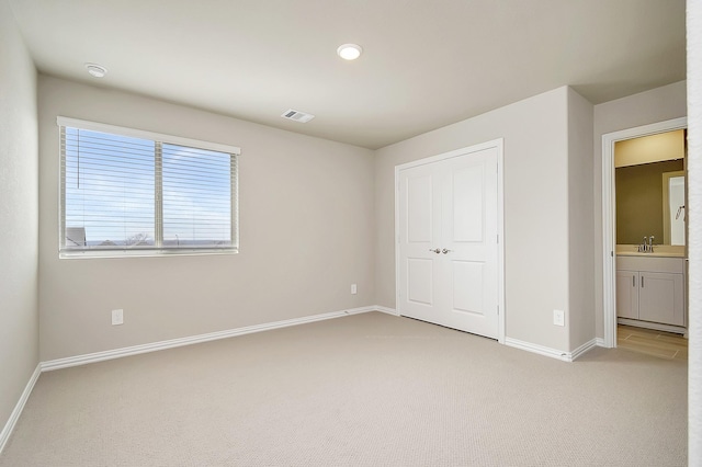 unfurnished bedroom with light colored carpet and a closet