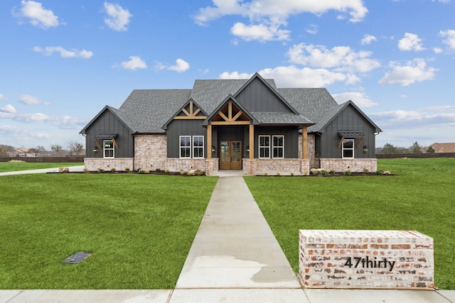 view of front of house featuring a front yard, brick siding, board and batten siding, and a shingled roof