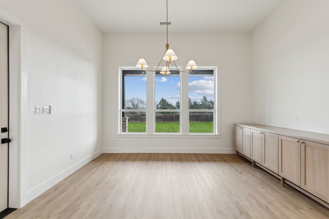 unfurnished dining area with a chandelier and light hardwood / wood-style flooring