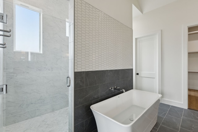 bathroom featuring shower with separate bathtub, tile walls, and tile patterned floors