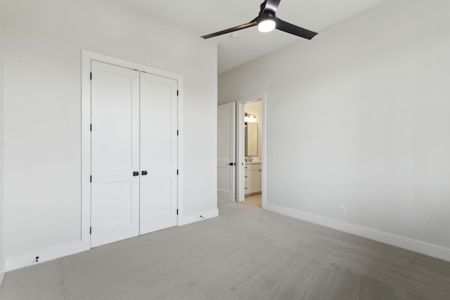 unfurnished bedroom featuring ceiling fan, light colored carpet, ensuite bathroom, and a closet