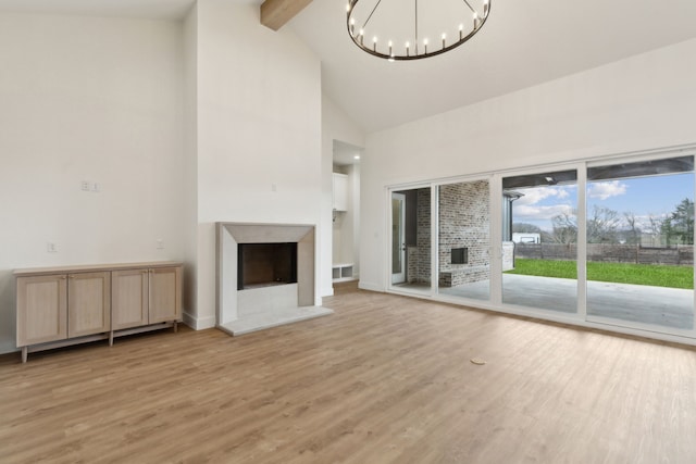 unfurnished living room with light hardwood / wood-style flooring, high vaulted ceiling, beamed ceiling, and a chandelier