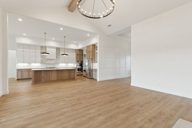 kitchen with hanging light fixtures, stainless steel appliances, light wood-type flooring, and a spacious island